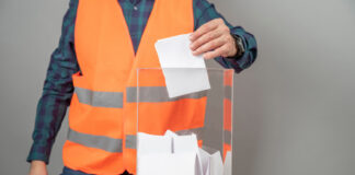 homem usando um uniforme de trabalho colocando papel em uma caixa de vidro