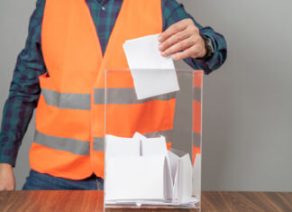 homem usando um uniforme de trabalho colocando papel em uma caixa de vidro