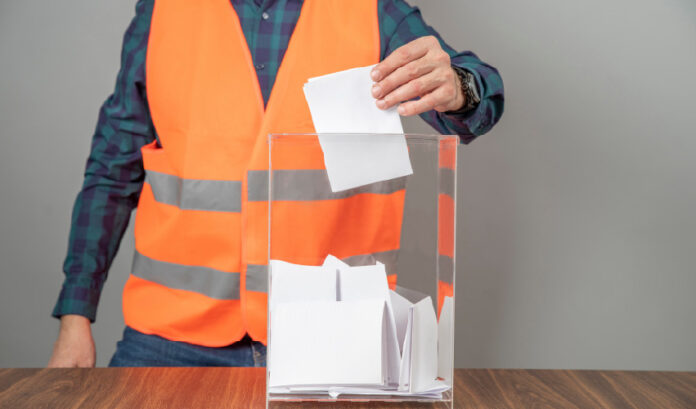 homem usando um uniforme de trabalho colocando papel em uma caixa de vidro