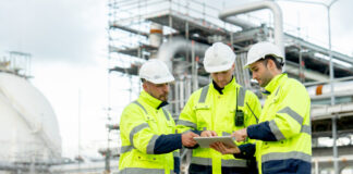 Engenheiros estão em frente à fábrica petroquímica e usam tablet para discutir seu trabalho.